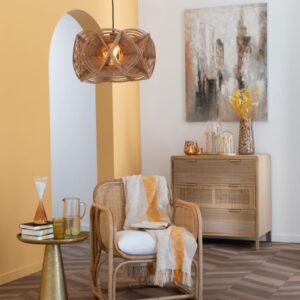 commode 3 tiroirs en bois et rotin dans un salon mur jaune plancher marron avec fauteuil lui nue en rotin table d'appoint couleur or