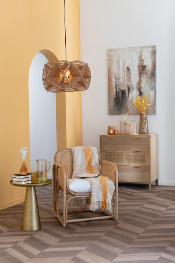 commode 3 tiroirs en bois et rotin dans un salon mur jaune plancher marron avec fauteuil lui nue en rotin table d'appoint couleur or