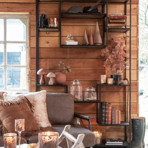 Étagère étagère 10 planches en bois de manguier et fer de couleurs brun foncé et noir dans un salon situé à côté d'une fenêtre avec table basse en forme de luge en bois blanc et canapé gris avec tapis en peau de vache blanc et marron