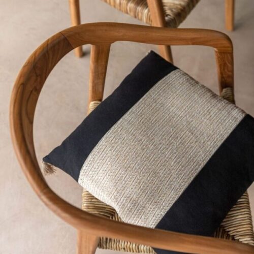 coussin tissage carré en polyester noir et beige posé sur une chaise en bois
