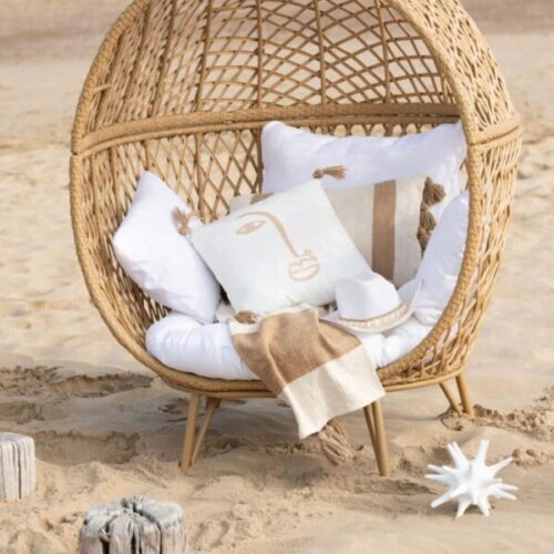 fauteuil extérieur en rotin coussin blanc avec visage beige en polyester coussin rectangulaire blanc avec rayures beiges coussin rectangulaire blanc sur le sable au bord de l'eau