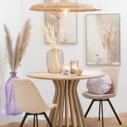 suspension en rotin table ronde en bois de manguier naturel chaises beiges avec pieds en métal noir vase haut translucide violet avec herbes pampas vase haut transparent blanc cadre gris et beige coussin violet rond dentelles en coton