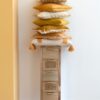 petite armoire fine en bois et rotin naturel tas de coussins posés dessus dans les teintes ocre orangées