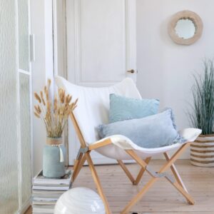coussin rectangle avec franges en velours bleu fauteuil lounge en bois et tissu blanc vase céramique bleu ciel avec herbes de pampas
