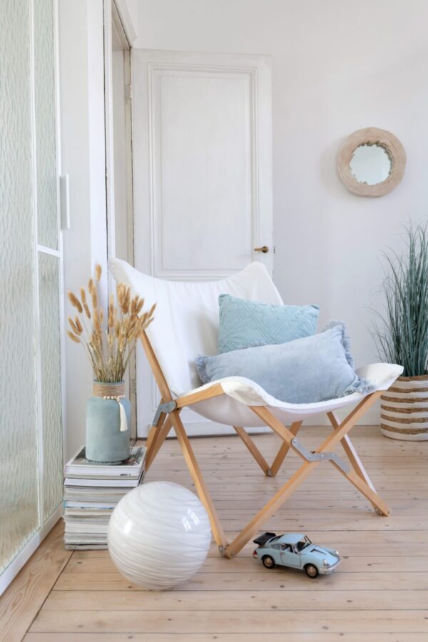 coussin rectangle avec franges en velours bleu fauteuil lounge en bois et tissu blanc vase céramique bleu ciel avec herbes de pampas