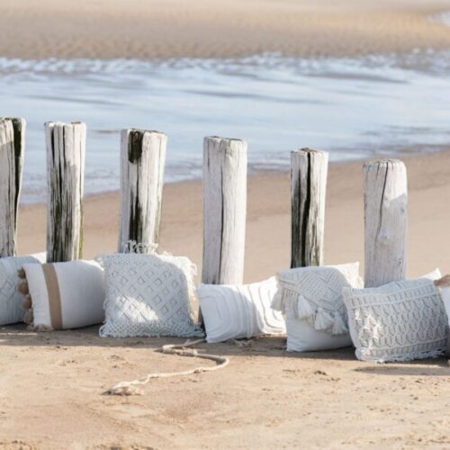 coussin en coton représentant des losanges sur une plage au bord de l'eau aligné avec d'autres coussins