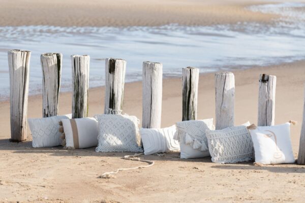 coussin en coton représentant des losanges sur une plage au bord de l'eau aligné avec d'autres coussins