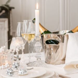 table de repas de fête blanche assiettes en porcelaines blanches verres à pied seau à champagne en acier inoxydable argent de forme ovale