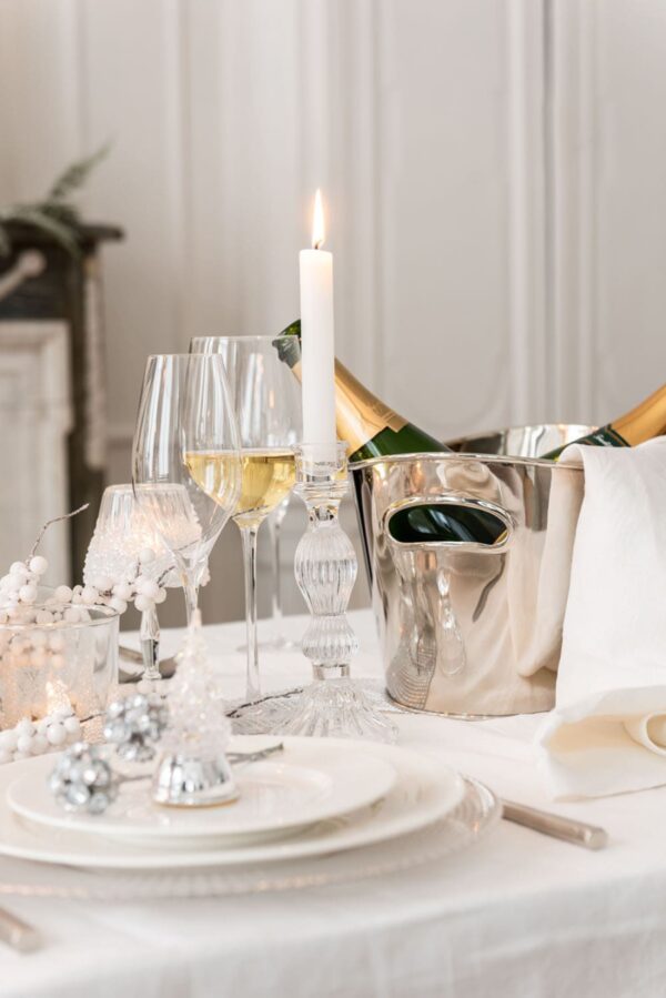 table de repas de fête blanche assiettes en porcelaines blanches verres à pied seau à champagne en acier inoxydable argent de forme ovale