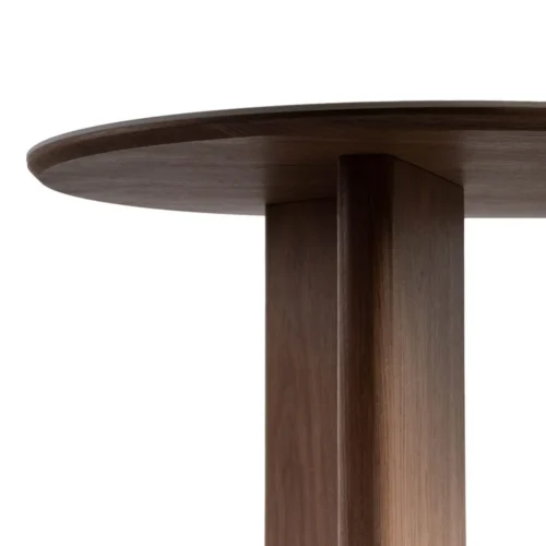 Jonction entre le chant arrondi du plateau céramique et le piètement noyer de la table Ixia